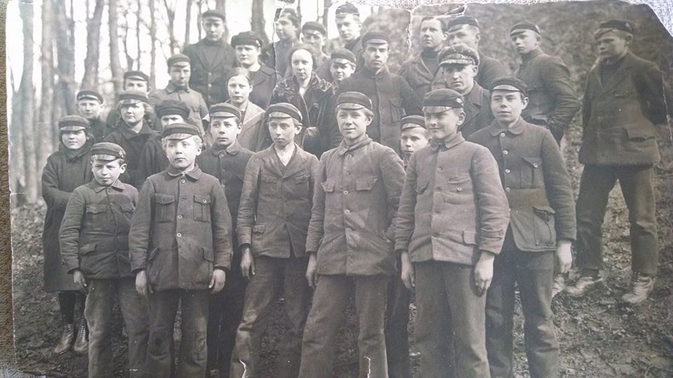 Vēsturiska melnbalta fotogrāfija ar Nīcas Lauksaimniecības skolas audzēkņu grupu mežā
